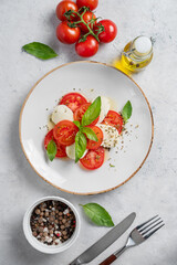 Flat lay of caprese salad with sliced ​​tomatoes, mozzarella and basil  on a light background