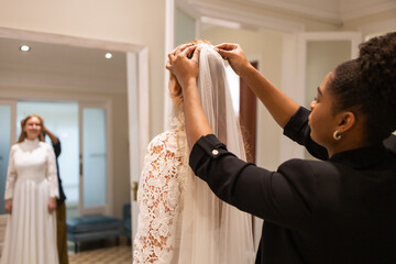 Bride Prepares as Stylist Adjusts Veil in Bridal Boutique