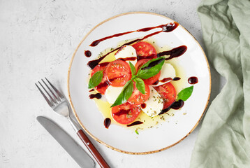 Fresh Caprese salad with sliced ​​tomatoes, mozzarella cheese, basil leaves and balsamic glaze