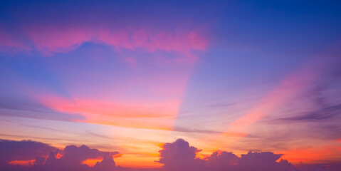 Sunset sky background with colorful pink and orange spectacular light beam and clouds on blue dramatic evening sky, Beautiful fantastic dusk sky after sundown
