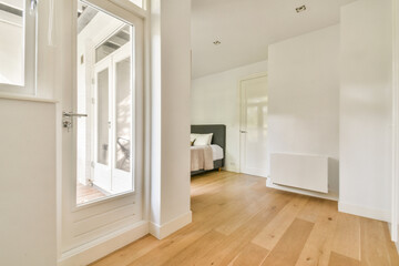 A stylish and airy interior featuring wooden flooring, white walls, and large windows. The...
