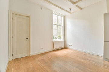 An inviting interior space showcasing large windows allowing abundant natural light, complemented by wooden flooring and minimalist design elements.