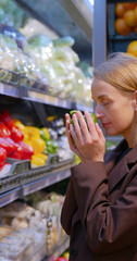 Woman choosing and smells red bell pepper while selecting vegetables