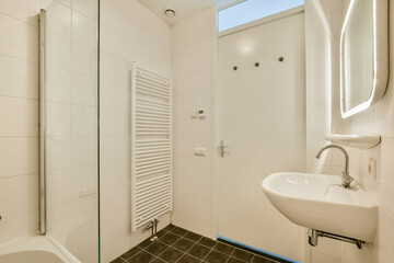Features a sleek bathroom with minimalist design, showcasing clean lines, white tiles, and modern fixtures for a contemporary look.