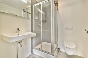 A sleek and contemporary bathroom featuring a glass shower enclosure, minimalist sink, and stylish toilet, designed for modern living and efficient use of space.