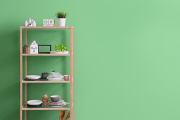 Shelf unit with dinnerware near green wall