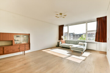 Bright and airy minimalist living room featuring a simple sofa and elegant wooden furniture, accentuated by large windows for natural light.