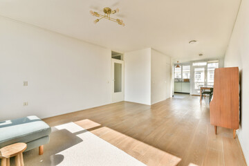 A spacious, light-filled room featuring minimalist decor with wooden flooring and simple furniture, creating a serene environment.