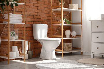Interior of restroom with toilet bowl, shelf units and plants