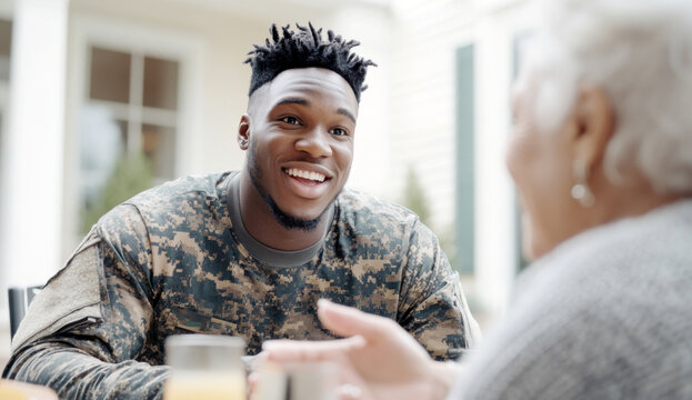 Young african american soldier smiling at elderly woman in cozy home setting