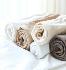 Rolls of linen fabric in various neutral tones arranged on table, background