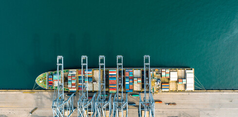 Top view of a large cargo ship loading and unloading containers at a deep-sea port. This aerial scene highlights global logistics, international trade, and maritime transportation hubs.