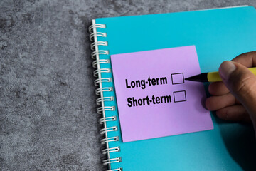 Concept of Long-term or short-term write on sticky notes isolated on Wooden Table.
