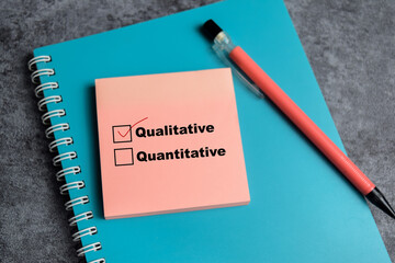 Concept of one person is answering question. he is choosing between qualitative and quantitative write on sticky notes isolated on Wooden Table.