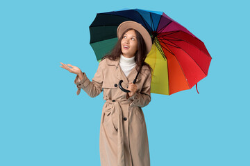 Beautiful young Asian woman with umbrella on blue background