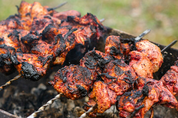 Shish kebab of meat on skewers is fried on the grill, green background
