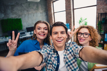 Obraz premium Young professionals posing for a selfie in a modern coworking office, showcasing teamwork and friendly collaboration