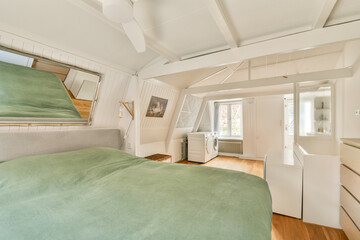A bright, modern bedroom featuring a soft green bedspread, wooden flooring, and contemporary furniture, creating an inviting and stylish atmosphere.