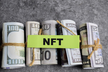 Concept of NFT - Non-fungible token write on sticky notes with dollars isolated on Wooden Table.