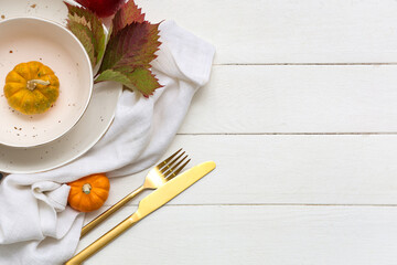 Beautiful table setting with pumpkins and autumn leaves on white wooden background