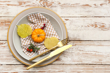 Beautiful table setting with golden cutlery and autumn decor on light wooden background