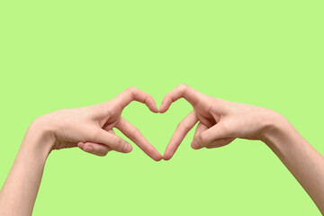 Obraz premium Female hands showing heart gesture on green background