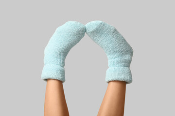 Legs of young woman in warm blue socks on grey background