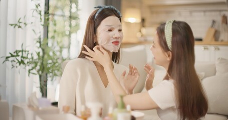 Two Asian women friends applying sheet masks together during beauty daily routine at home. Girl talk, skincare bonding moment, Gen Z lifestyle, self care and relaxing feminine friendship vibe.