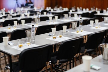 Glasses of whiskey await attendees in an empty conference hall during an event