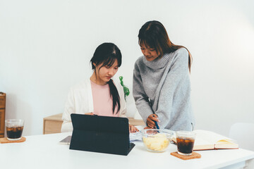 Female higher education student using laptop and studying book in home, Online learning.