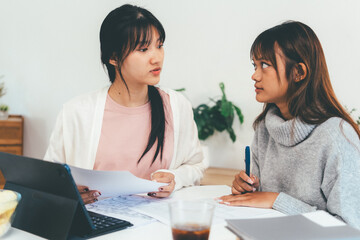 Female higher education student using laptop and studying book in home, Online learning.