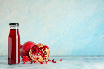 Bottle of fresh pomegranate juice and fruits on light blue background