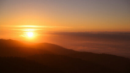 Fototapeta premium Dramatic sunrise or sunset views over a misty mountain landscape