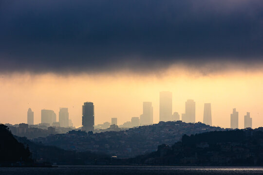 Skyscrapers and hills at sunset with partly cloudy sky