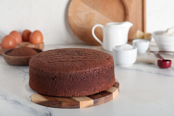 Delicious chocolate sponge cake with ingredients on marble table