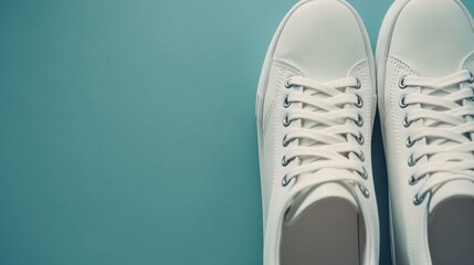 Fototapeta premium Pair of clean white sneakers on teal background