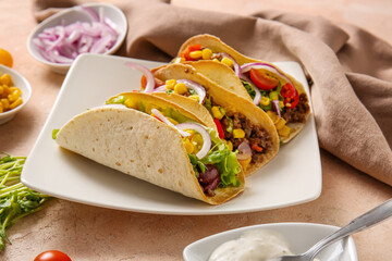 Plate with fresh tasty tacos on beige grunge background