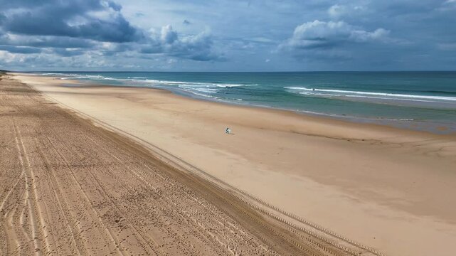 Surfeur solitaire planche sous le bras devant oc&eacute;an bleu vagues battantes