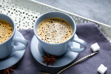 Cups of hot coffee and star anise on black background