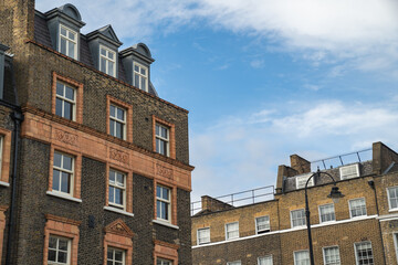 Traditional Terraced Houses Line a Quiet Street with Green Trees and a Red London Bus in View Reflecting the Calm Atmosphere of the Neighborhood.