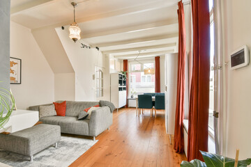 A contemporary living room featuring a cozy grey couch, wooden floors, and elegant lighting, offering a warm and inviting atmosphere. Perfect for relaxation or gatherings.