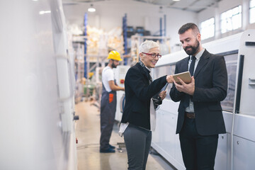 Quality inspectors team and workers at factory using machines