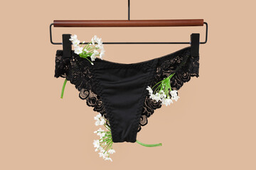 Female lace panties with flowers hanging on beige background