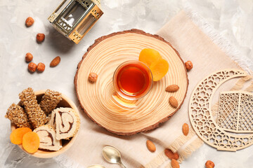 Glass of tasty Turkish tea with sweets, crescent and fanoos on white grunge background. Ramadan celebration