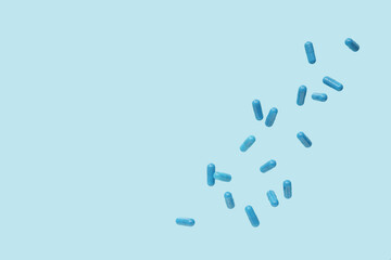 Flying blue pills on color background