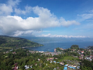 Naklejka premium Aerial 4K drone footage of Lake Toba in North Sumatra, Indonesia, with clear blue sky, calm water, and lush green hills. Perfect tropical landscape for travel and nature themes