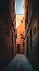Obraz premium A narrow alleyway with old brick and plaster walls captures the essence of a quaint European town. The sunlight illuminates the orange hues, creating a cozy atmosphere