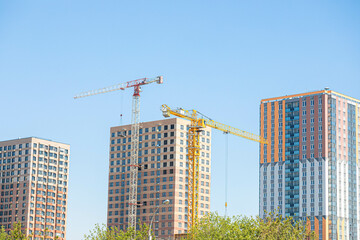 Modern high rise buildings under construction with tower cranes. Urban residential development.