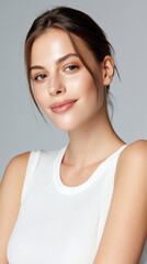 A woman with a white tank top and brown hair is smiling