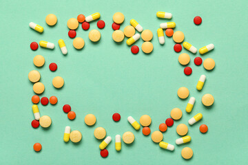 Frame made of different pills on green background